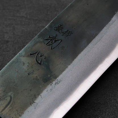 Gyuto blade in close-up with kanji engraving on the surface.