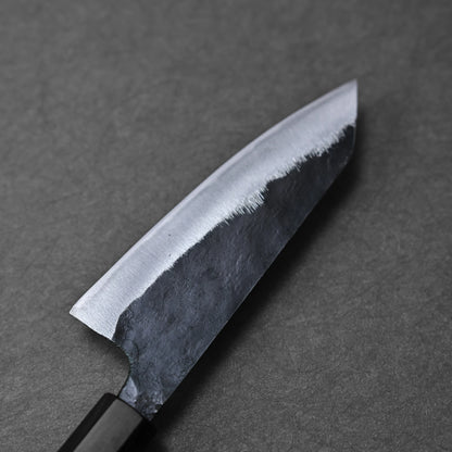 Close-up of the Hatsukokoro Kurouchi Aogami#2 Ko-Bunka 120mm kitchen knife by Hatsukokoro, featuring a black handle and a partially polished Aogami #2 blade on a dark matte surface.