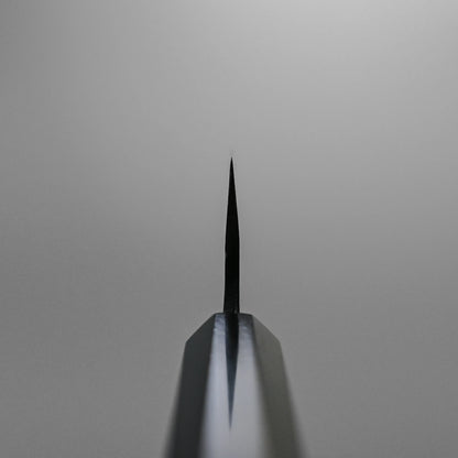Choil shot of the Hatsukokoro Kurouchi Aogami#2 Ko-Bunka 120mm knife tip, centered against a plain light gray background. The blade displays Hatsukokoro’s signature kurouchi finish and is crafted from premium Aogami #2 steel.