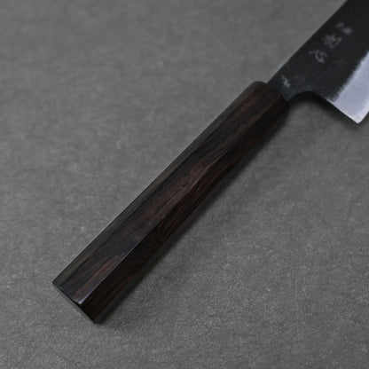 A close-up of the Hatsukokoro kurouchi aogami#2 ko-bunka 120mm knife, featuring a dark wooden handle and partially visible Aogami #2 blade from Hatsukokoro, resting on a gray textured surface.