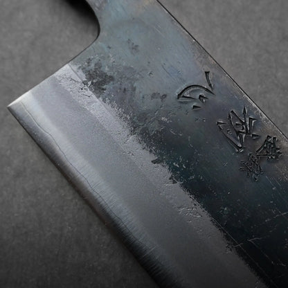Visible portion of the Japanese knife shows a textured, dark kiritsuke gyuto blade with engraved markings.