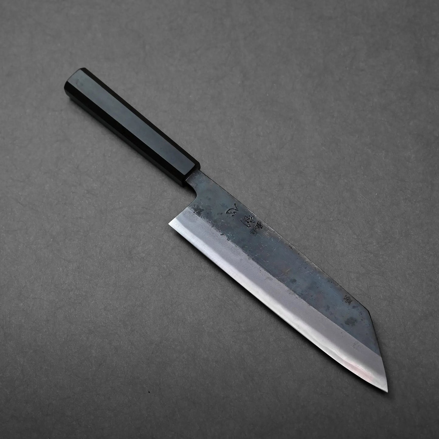 Straight-edged blade and black handle of a Japanese knife, kiritsuke gyuto style, blade finish appears smooth.