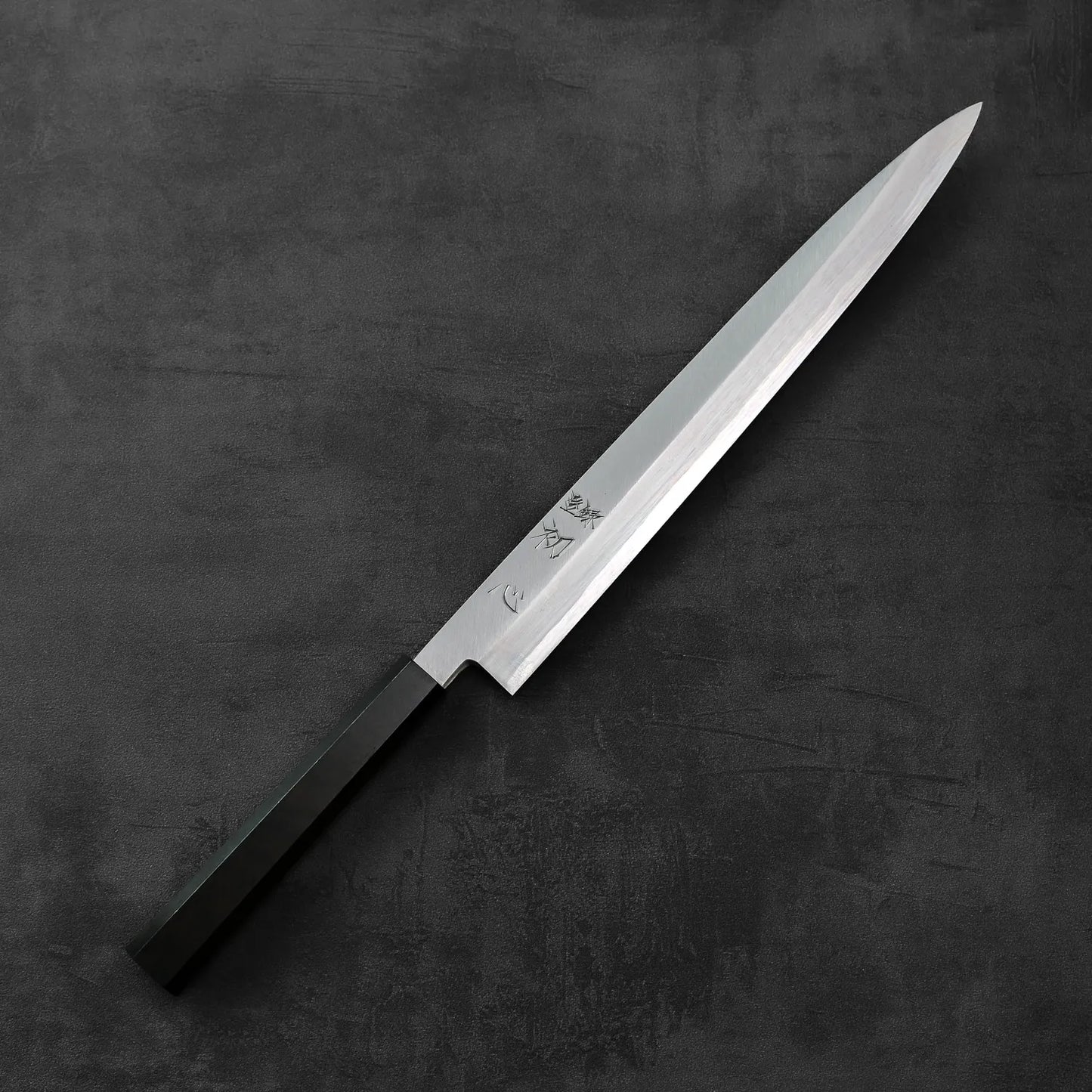Hatsukokoro x Nakagawa aogami#1 yanagiba 300mm with a dark handle, showing distinct lines and polished finish under soft lighting.