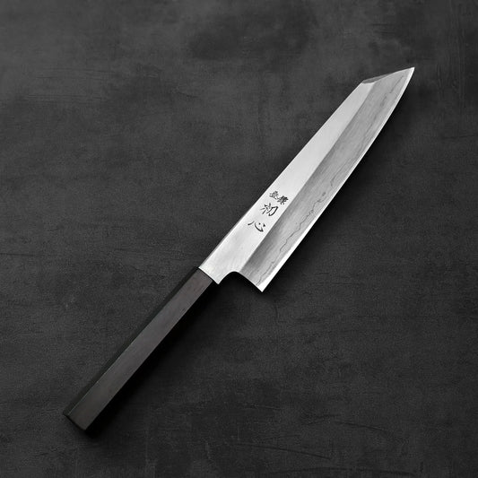 Hatsukokoro x Nakagawa ginsan kiritsuke gyuto 210mm with a black handle is shown, highlighting its distinct silhouette and smooth lines.