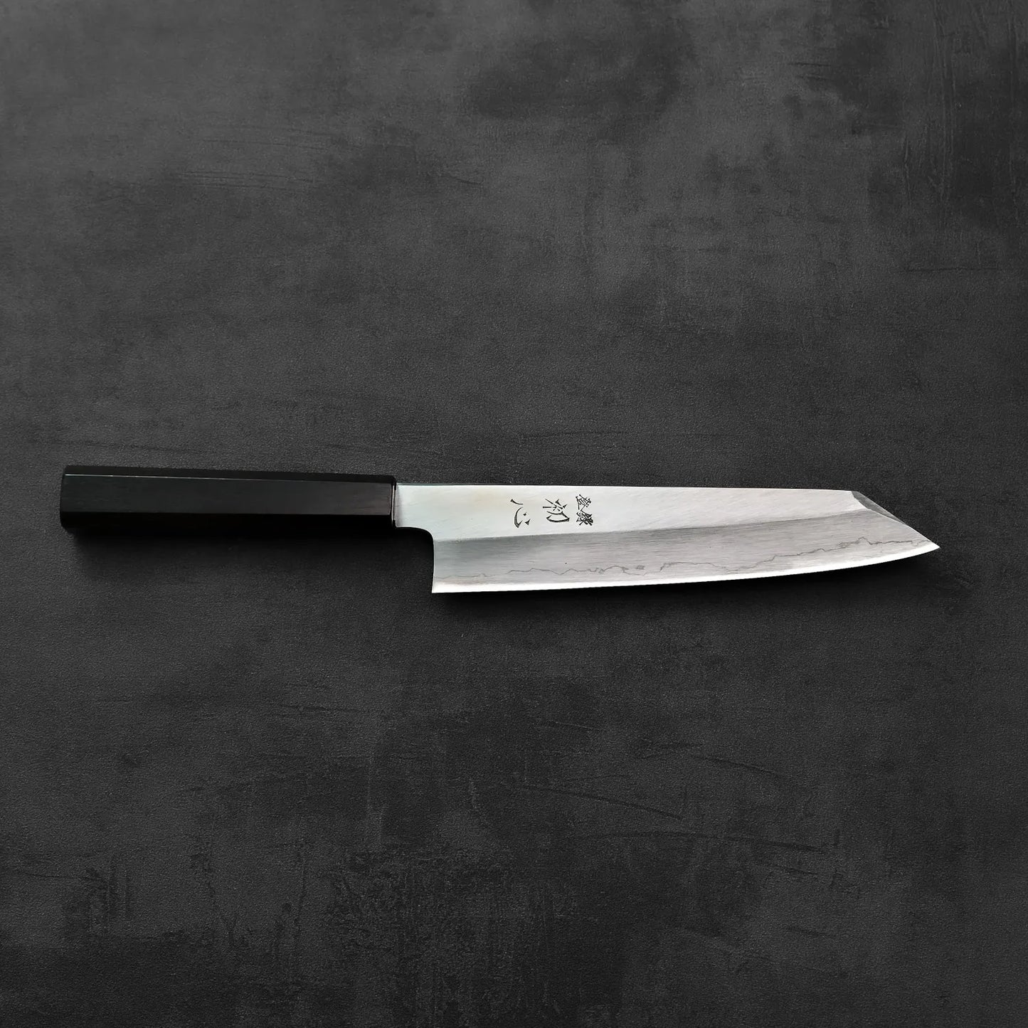 Kiritsuke gyuto with a black handle is shown, highlighting the silhouette and detailing of the blade.