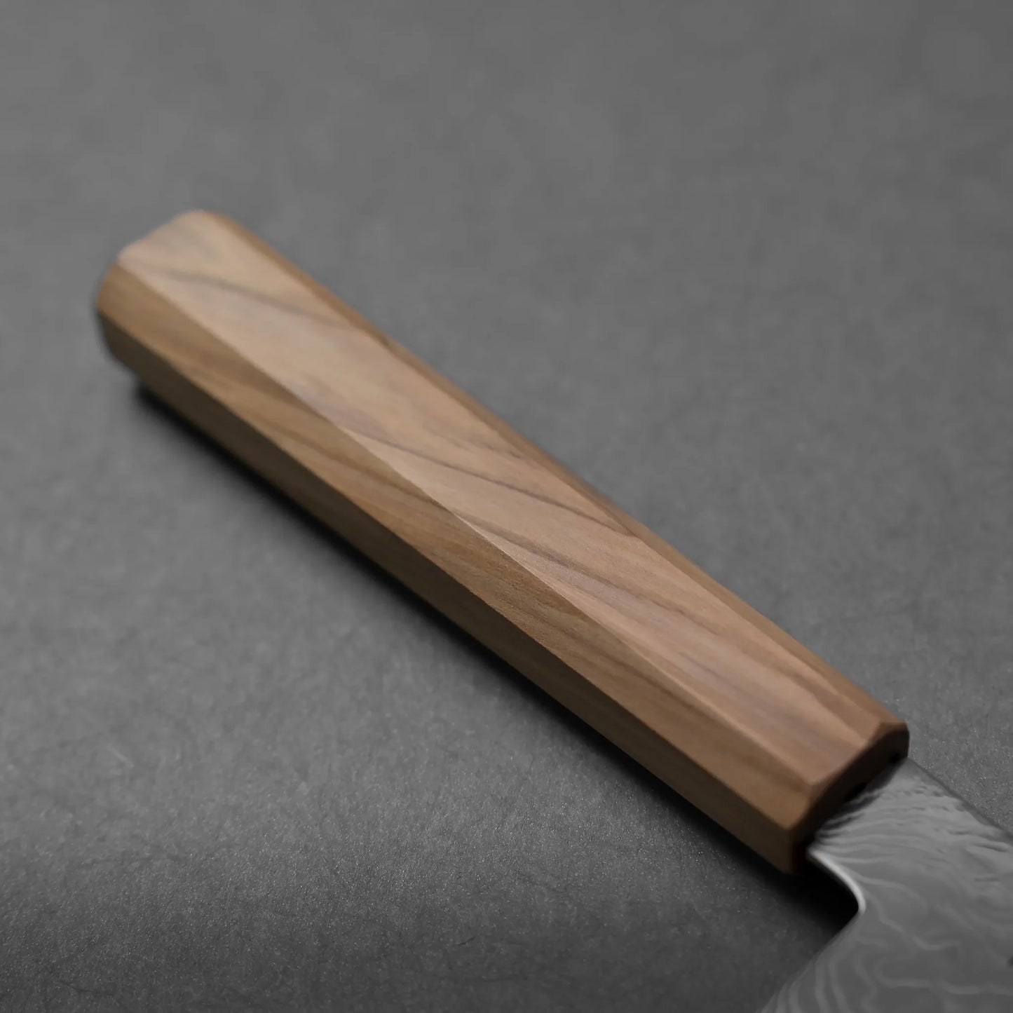 Close-up of a wooden knife handle with visible grain patterns, paired with a stainless steel blade, set against a dark gray background.