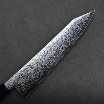 A close-up of a kiritsuke Japanese chef knife with a patterned Damascus steel blade and a dark handle, set against a plain, dark background.