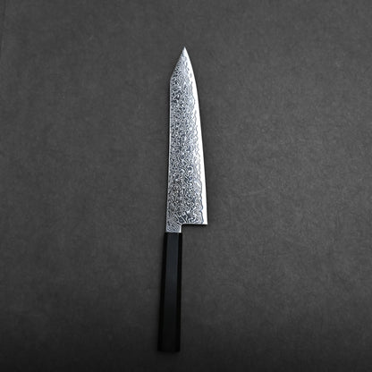 A single kiritsuke Japanese chef knife with a patterned blade and a black rectangular handle is placed on a dark, plain surface.