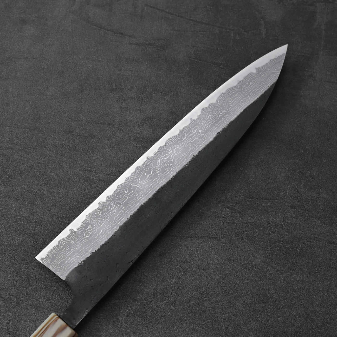 A gyuto with a damascus pattern and AS steel blade is displayed, highlighting its unique design details.