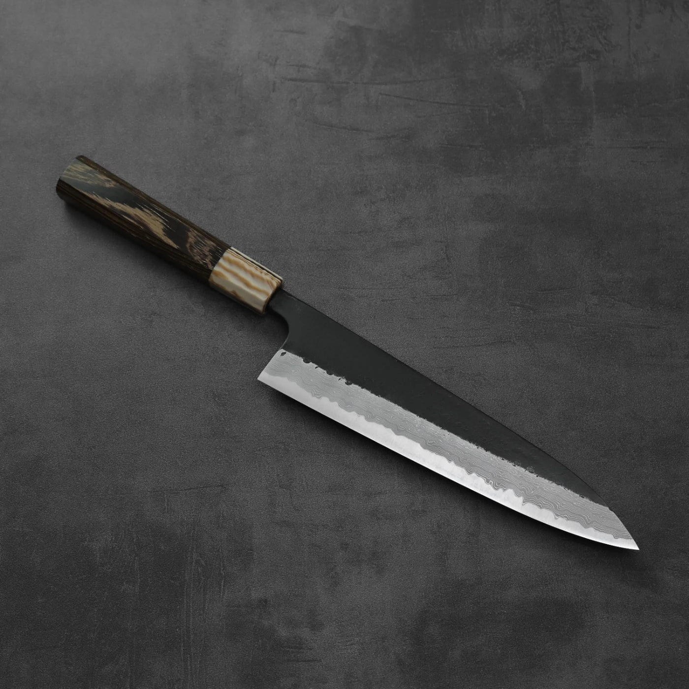 Gyuto with a dark handle, blade featuring kurouchi damascus steel pattern.