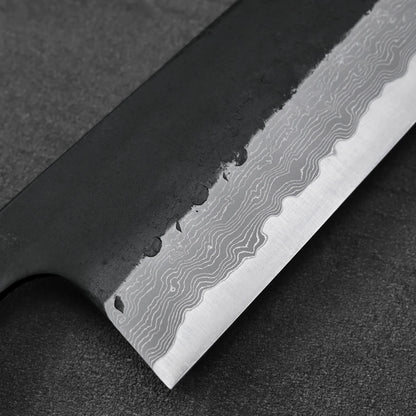 Gyuto with a close-up view of wavy Damascus steel patterns across the blade, highlighting its texture.