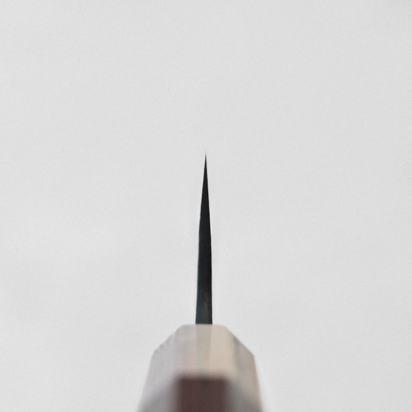 Close-up of gyuto tip, viewed from above, revealing damascus pattern and distinctive blade profile.