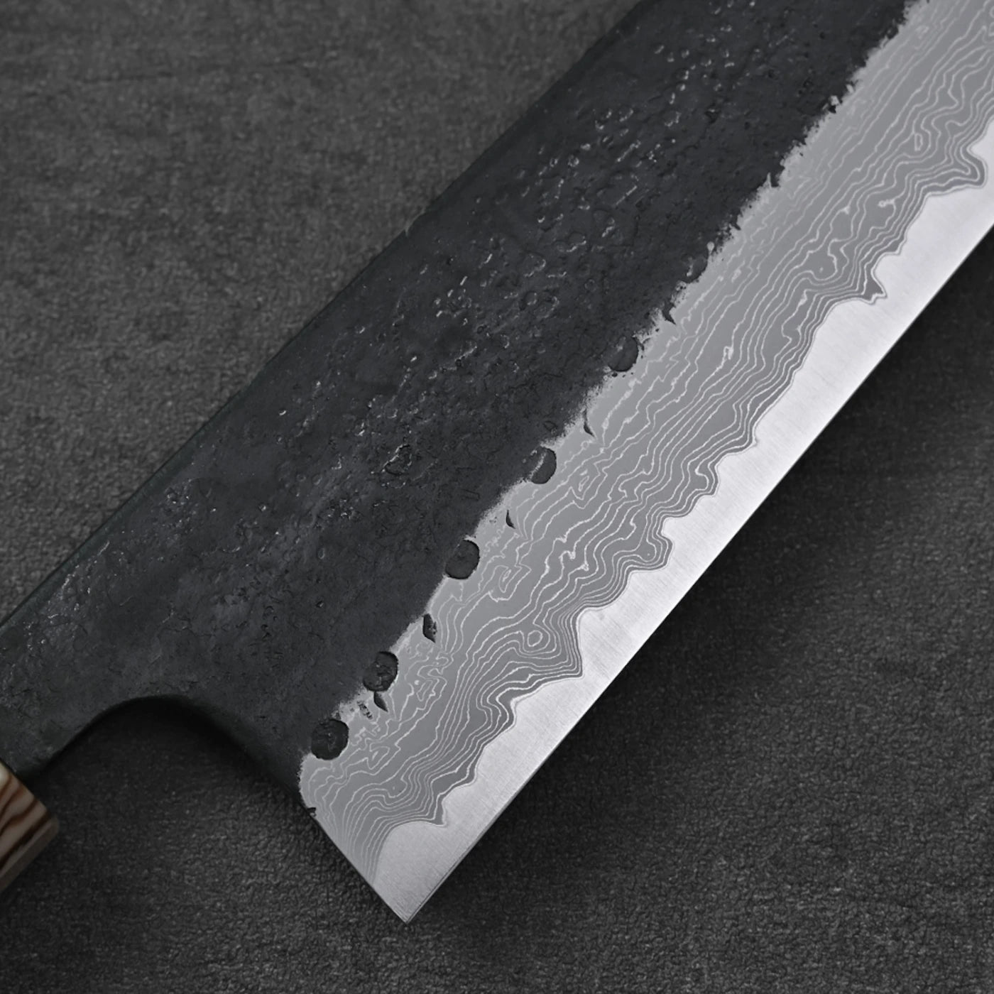 Close-up of gyuto with damascus blade and wooden handle.