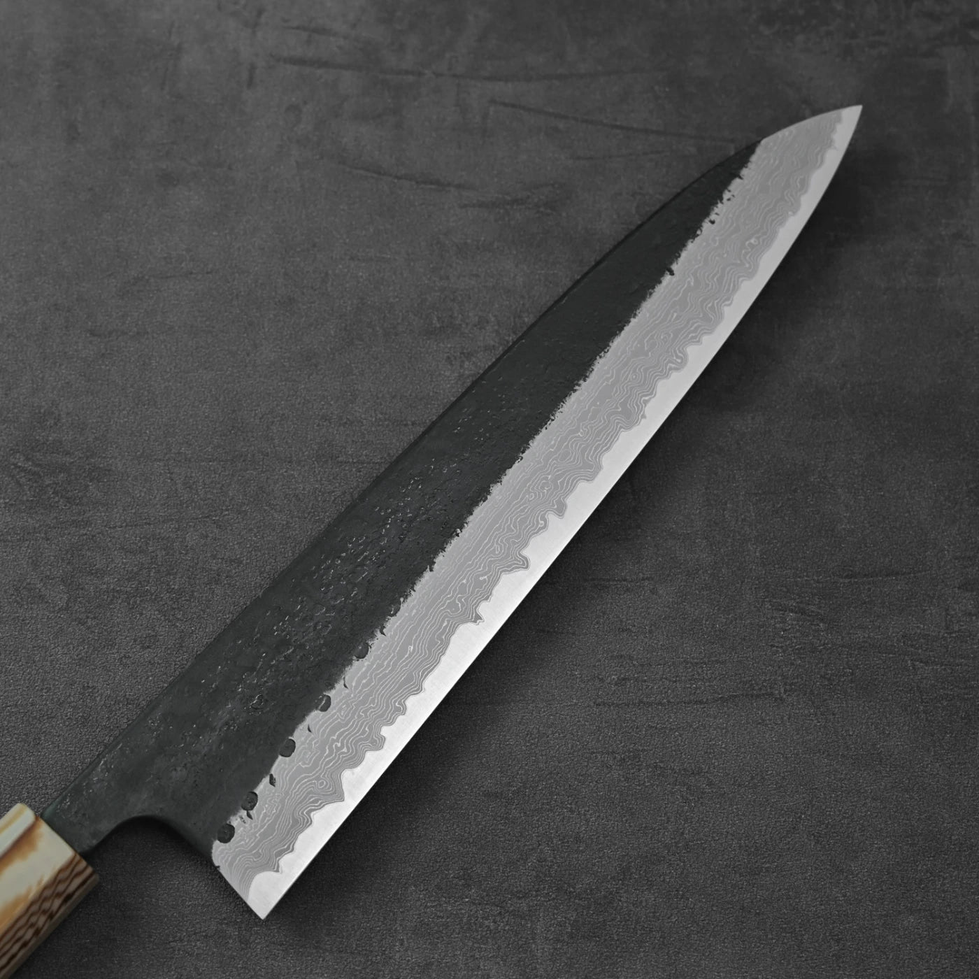 A gyuto with damascus blade and wood handle, featuring a kurouchi finish.