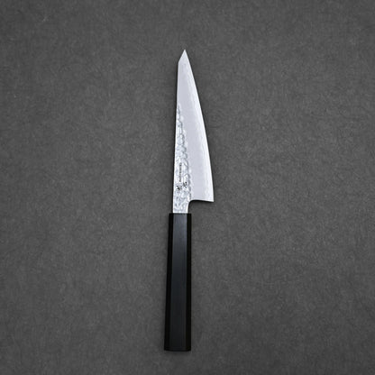 A Hatsukokoro tsuchime ginsan honesuki 150mm knife with a textured silver blade and black handle rests on a dark gray surface.