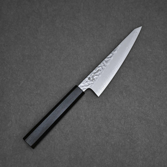 A Hatsukokoro tsuchime ginsan honesuki 150mm with a black octagonal handle rests on a dark textured surface.