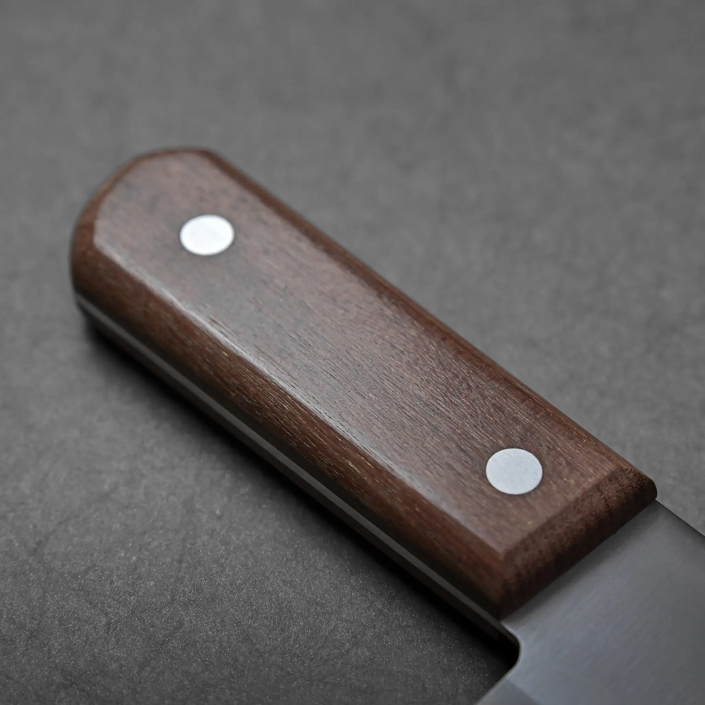 Close-up showing a Japanese knife handle from Tsubame-Sanjo, two metal rivets visible, blade not shown.
