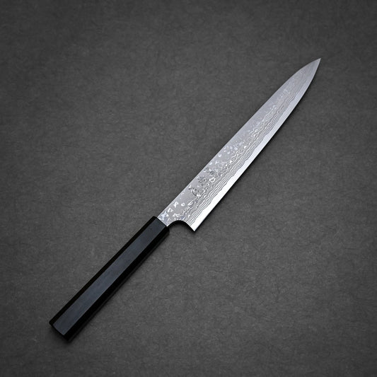 A Hatsukokoro x Yauji damascus aogami#2 yanagiba 240mm with a patterned blade and a black rectangular handle is placed on a dark gray textured surface.