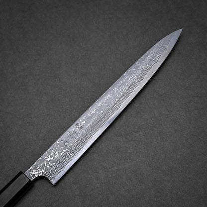 A Japanese-style damascus yanagiba with a long, narrow, and pointed blade featuring a visible Damascus steel pattern, set against a dark gray textured background.