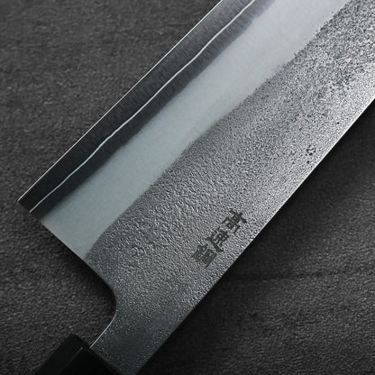Close-up of a gyuto blade, highlighting its polished and textured steel with distinct visual patterns.