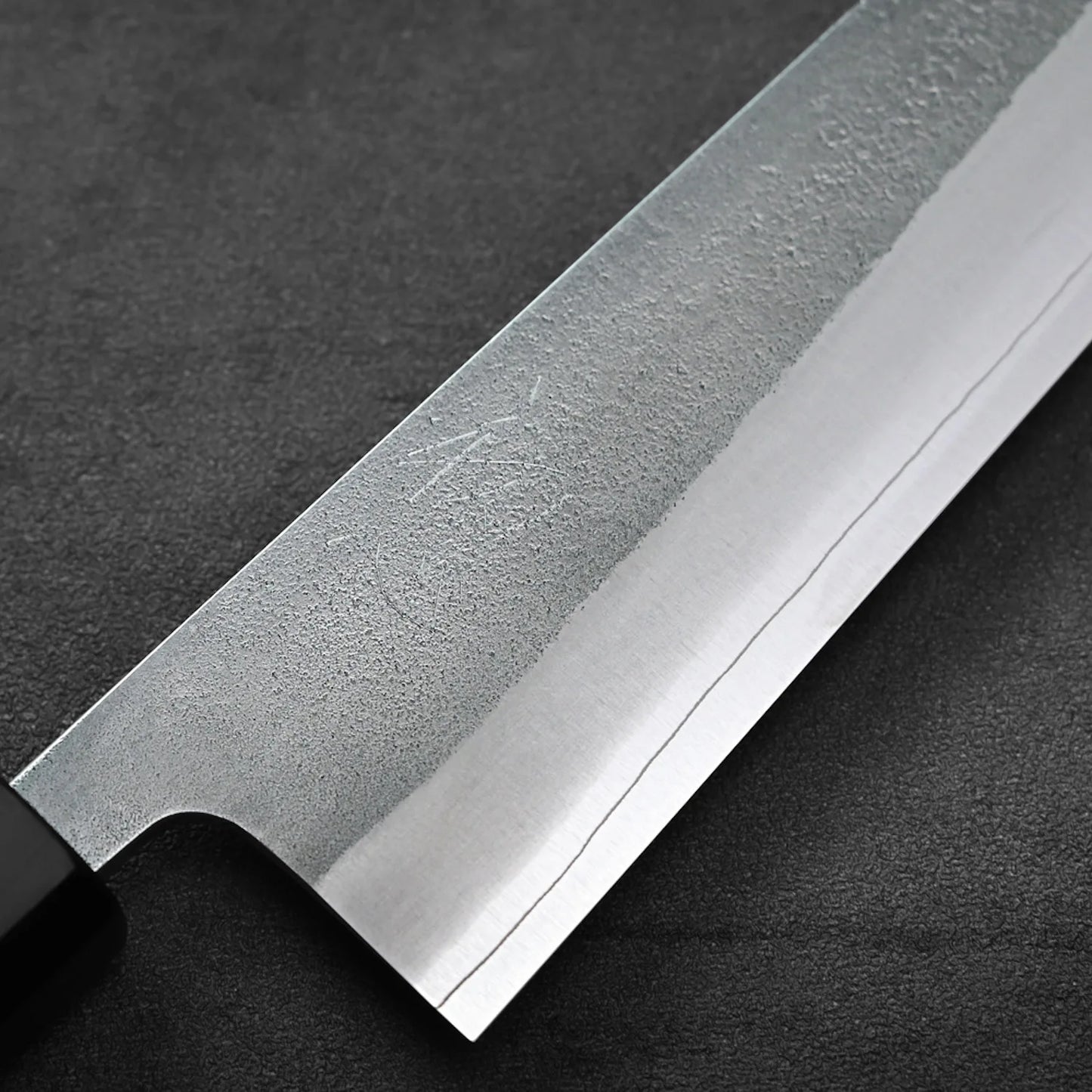 Close-up of gyuto blade, highlighting detailed pattern and steel construction, photographed tightly.