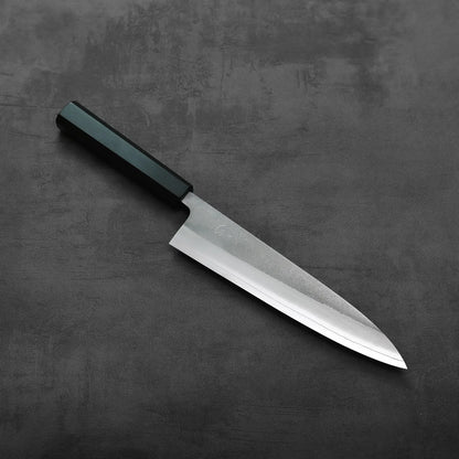 Gyuto with a black handle, 210mm blade, set alone and photographed to highlight its shape and design details.