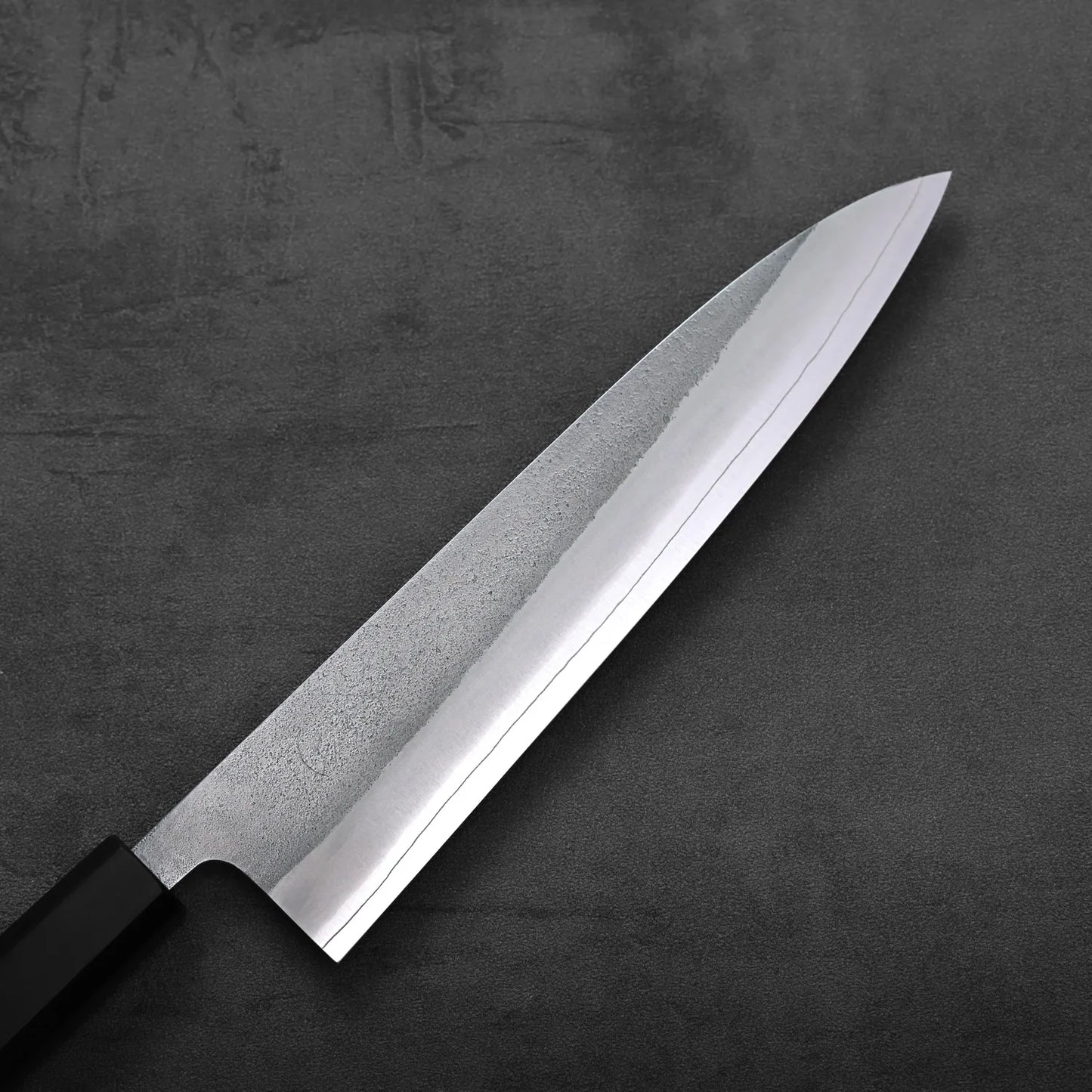 A close-up of a gyuto highlights the textured nashiji finish and 210mm blade from an overhead angle.