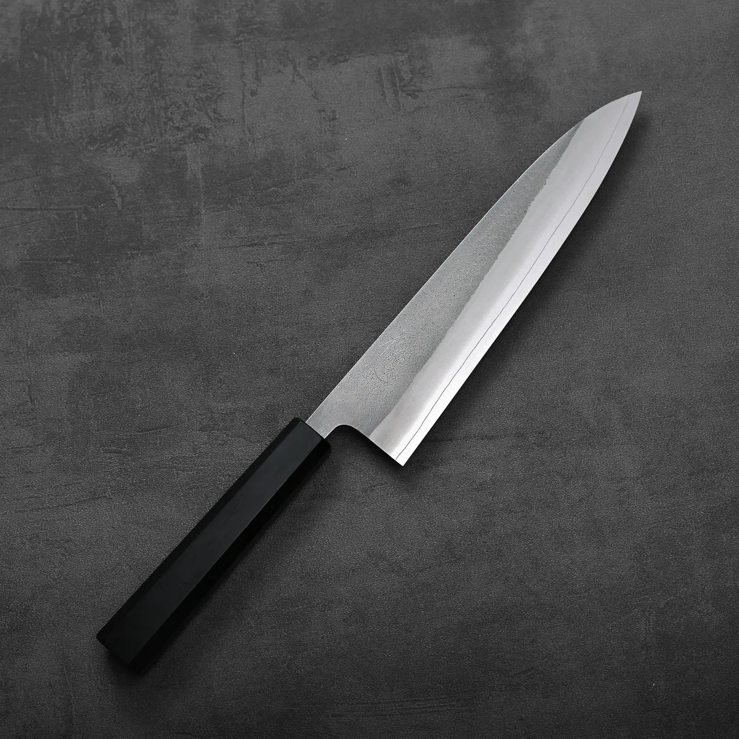 Gyuto with a black handle, showing subtle texture and distinct lines along the blade.