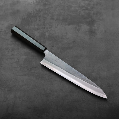 Gyuto with a dark handle, showing its blade and silhouette. No background or setting described.