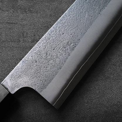 Gyuto blade shown in close-up with a textured, matte finish highlighting its detailed nashiji pattern.