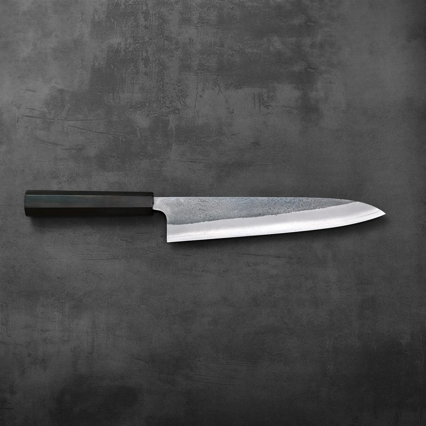 A gyuto with a distinctive nashiji finish is displayed, highlighting its refined blade texture and shape.