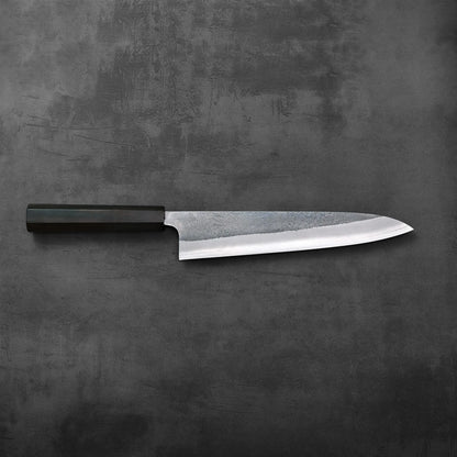 A gyuto with a distinctive nashiji finish is displayed, highlighting its refined blade texture and shape.
