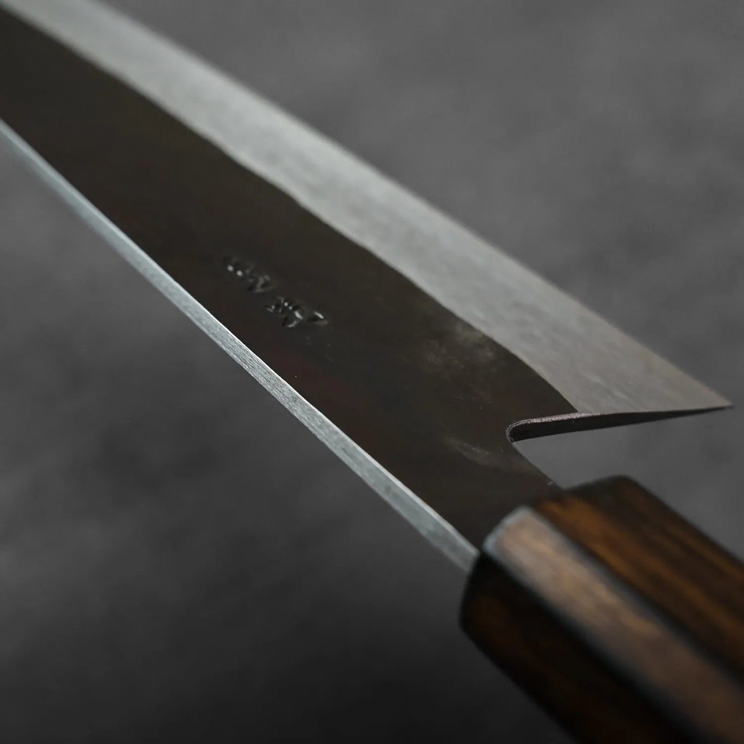 Close-up of a gyuto with wooden handle, blade details and contours clearly visible.