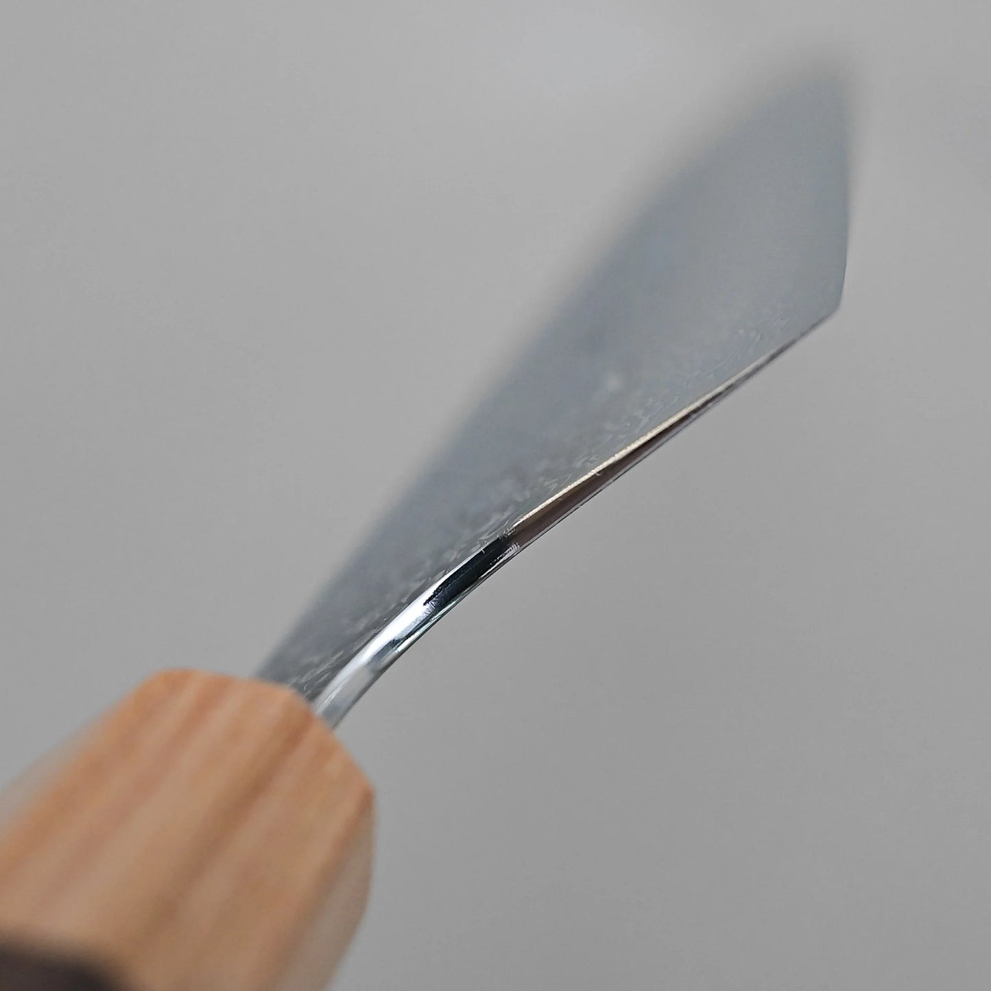 A close-up of the Kei Kobayashi SG2 damascus gyuto 240mm, featuring a wooden handle and a shiny, angled blade, photographed against a plain light gray background.