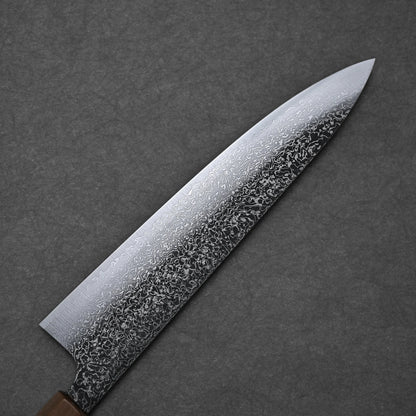 A close-up of the Kei Kobayashi SG2 damascus gyuto 240mm showcases intricate swirling patterns on its blade against a dark textured background, with its handle partially visible in the lower left corner.