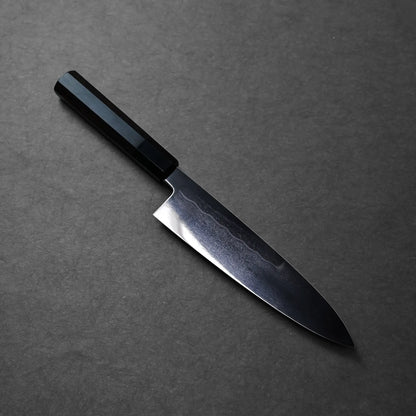 A dark-handled Japanese knife with a broad, curved blade and polished finish typical of a chef’s knife.