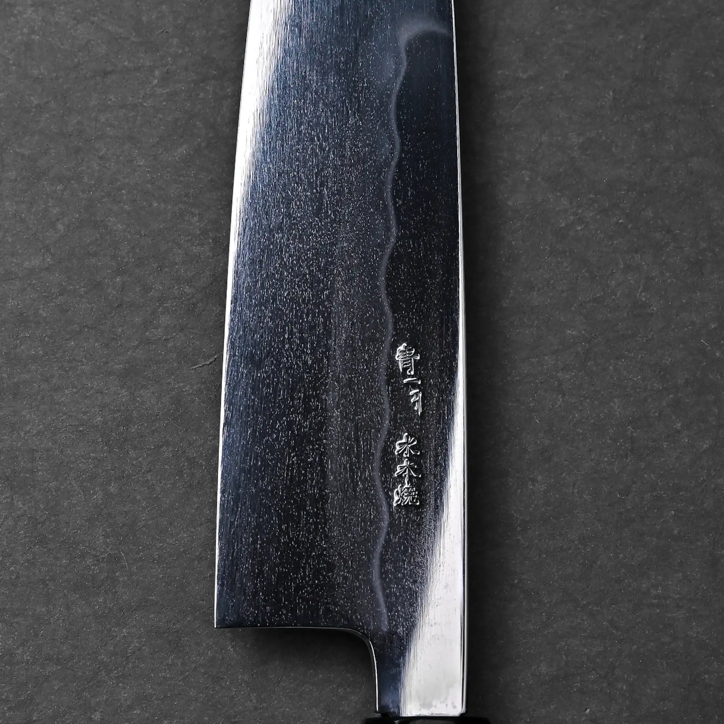 Engraved kanji on the visible part of a Japanese knife blade, close-up view of a Mizuhonyaki gyuto.
