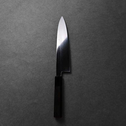 A Japanese knife, a Mizuhonyaki gyuto with a dark handle, shows its long curved blade and polished finish.