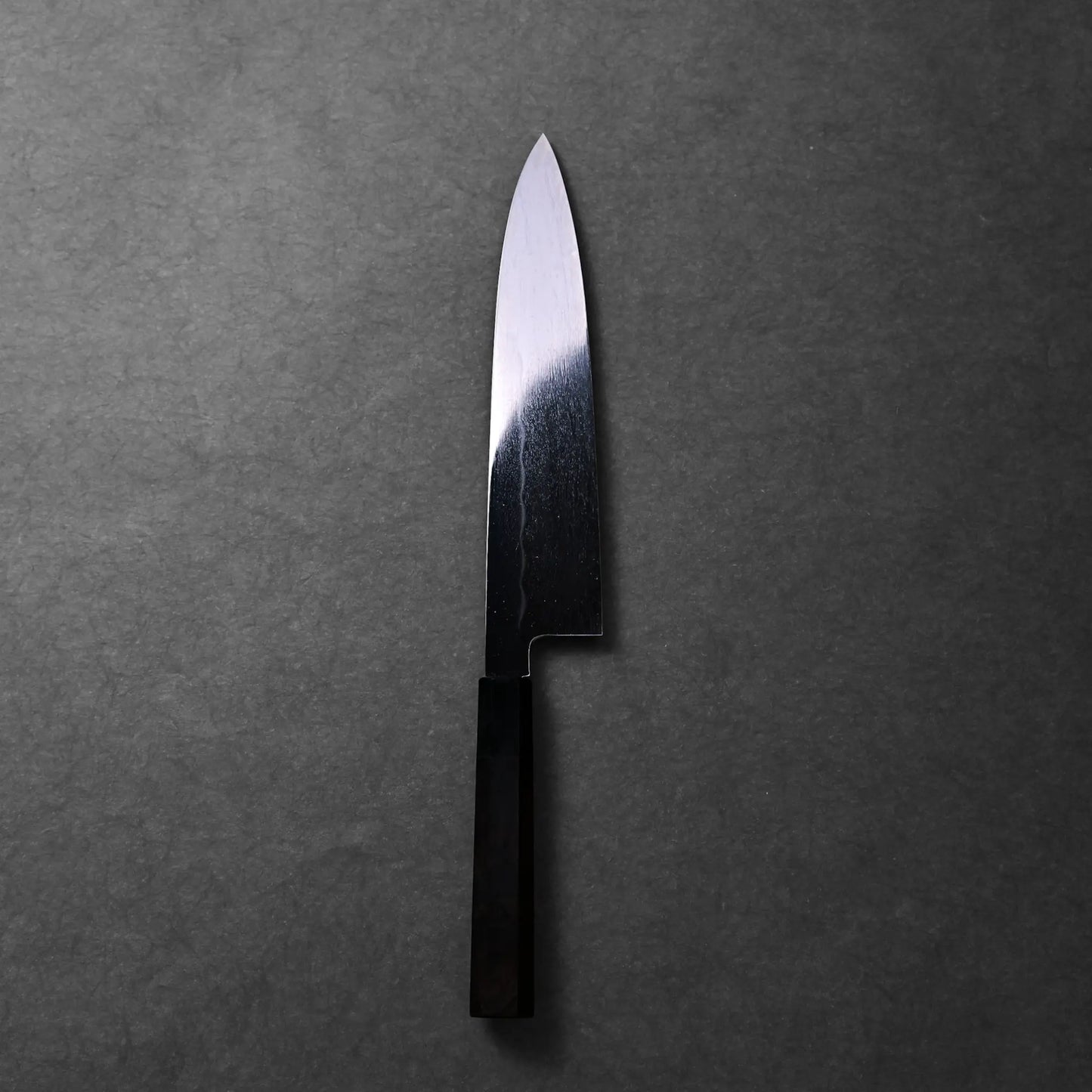 The image shows a Japanese knife, a Mizuhonyaki gyuto with a black handle and a straight-edged blade with subtle patterning.