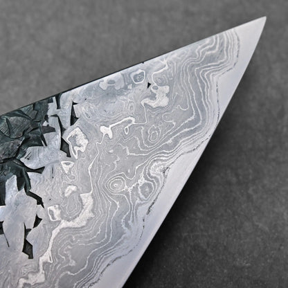 Close-up of the tip showing wavy Damascus pattern on a Japanese knife blade; specific type not discernible.