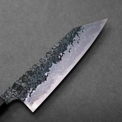 A blade with a kiritsuke gyuto shape and Damascus pattern, showing a hammered finish, is a Japanese knife.