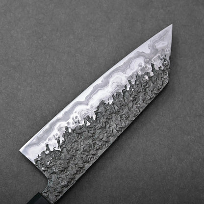 Close-up showing the textured damascus steel pattern of a Japanese knife, specifically a Kisuke Manaka bunka blade.