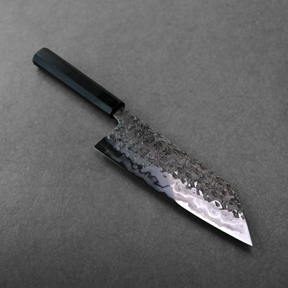 A hammered, wavy-patterned blade of a Japanese knife, bunka type, showing its angled tip and flat edge.
