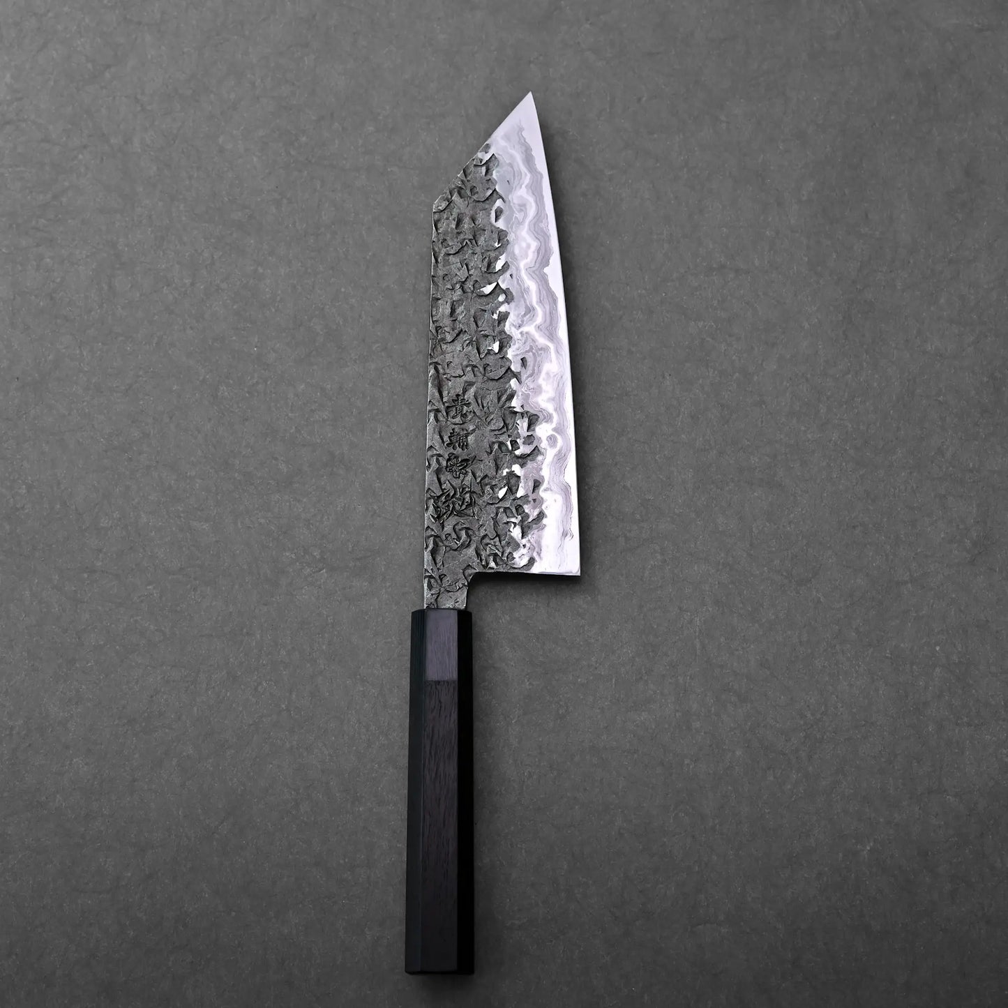 A patterned blade with an angular tip and dark handle on display; Japanese knife bunka type, Kisuke Manaka.