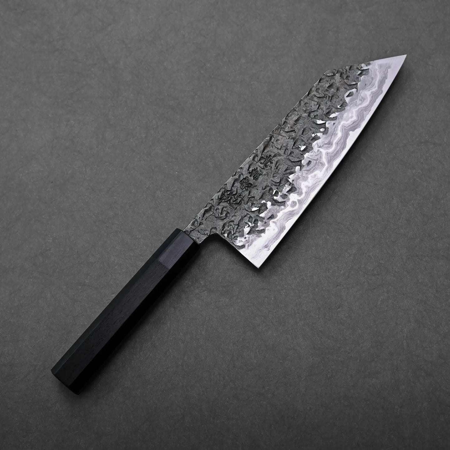 Close-up of a Kisuke Manaka ENN bunka 200mm patterned blade and dark handle, Japanese knife with bunka shape visible.