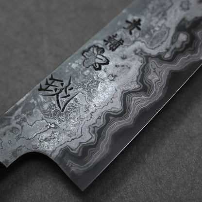 Close-up of a Damascus steel knife blade with engraved patterns on a dark background