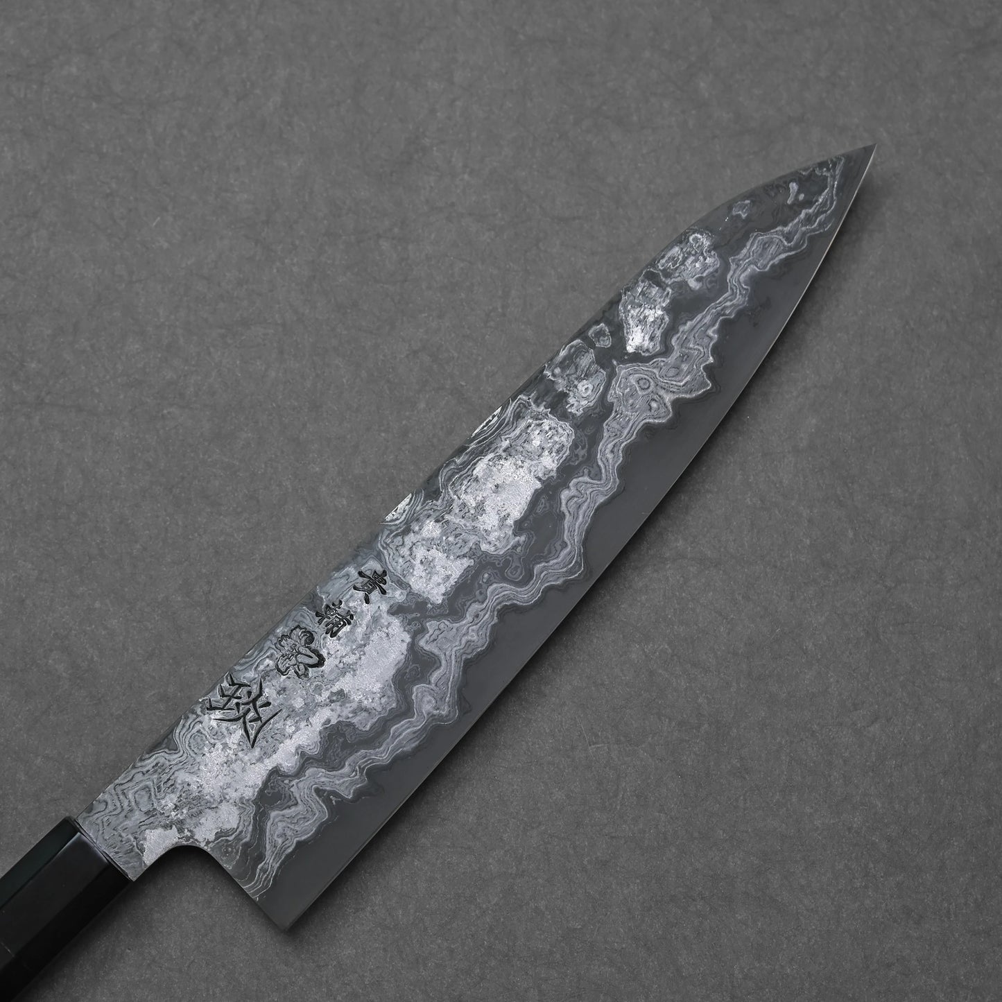 Damascus gyuto blade on a gray background
