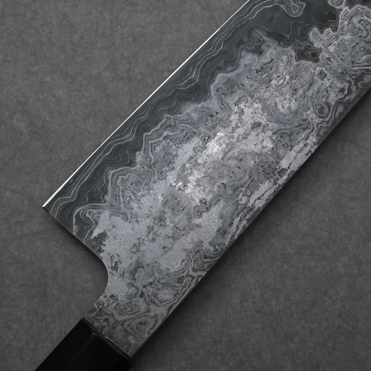 Close-up of a knife blade with a detailed pattern on a dark background