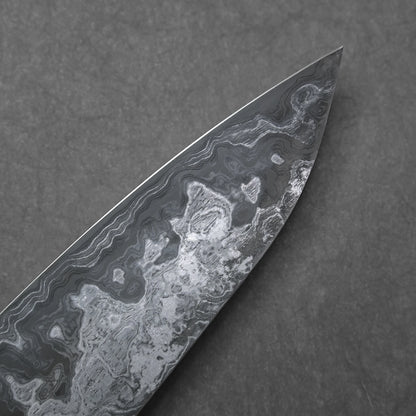 Close-up of a knife blade tip with a marbled damascus pattern on a dark gray background