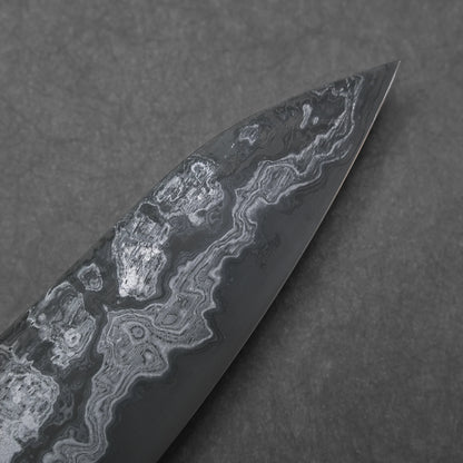 Close-up of a knife blade tip with a unique pattern on a dark background